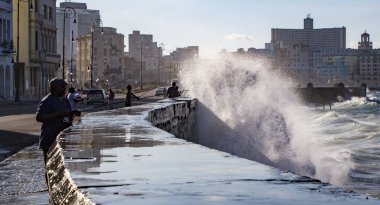 Havana, Küba - 19 Kasım 2011 - Duvarın üzerinden dalgalar geçerken körfezden balık avlamak için gençler beton bir duvara dizildiler