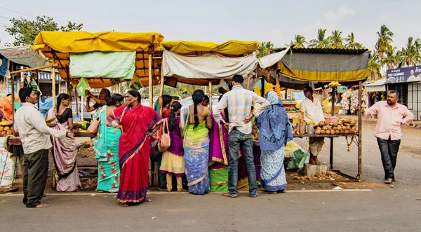 Люди товпляться довкола запасів їжі на малому придорожньому базарі, перш ніж іти додому. — стокове фото