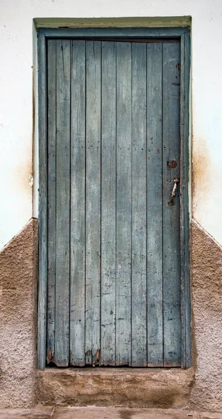 Wyblakłe zielone drzwi na brązowo-białej witrażu ściany — Zdjęcie stockowe