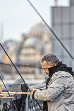 İstanbul, Türkiye - 1 Nisan 2016 - Erkekler oltasını köprüde balık tutmaya hazırlıyor