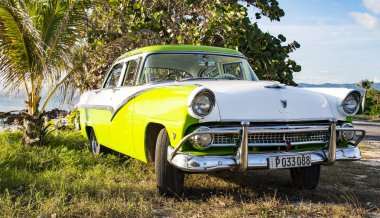 Yeşil beyaz Ford Fairlane plaja park etmiş.