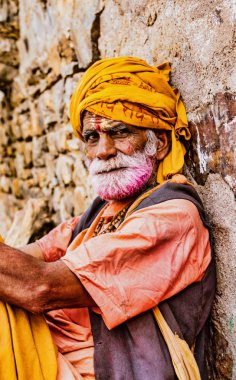 Barsana, Hindistan-23 Şubat 2018-gri sakal ve sarı türbin ile yaşlı adam Holi festivalinde yatıyor