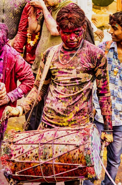 Barsana, indien - 23. februar 2018 - ein trommler schlägt eine melodie für die nachtschwärmer, während er beim holi festival mit farbe überzogen ist — Stockfoto