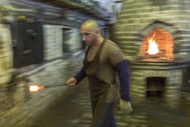 Demirci ocaktan erimiş metal taşıyor