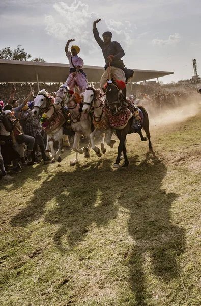 Zwei Männer reiten auf vier Pferden, auf dem Rücken stehend, während sie innerhalb von Zentimeter des Publikums rasen — Stockfoto