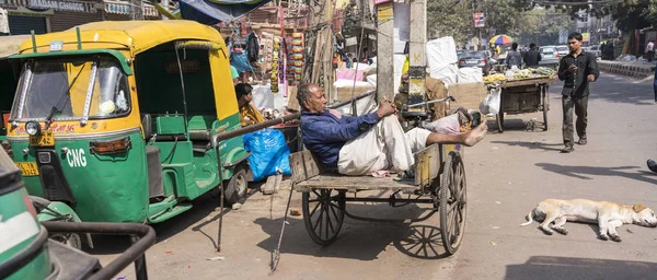 Nueva Delhi, India - 19 de febrero de 2018 - El hombre descansa en su carro de madera entre tareas —  Fotos de Stock