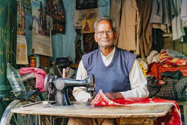 Barsana, Hindistan - 23 Şubat 2018 - Holi festivali sırasında sokak kenarındaki tezgahından bir terzi elbise dikti