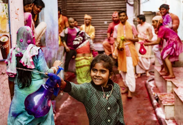 Girl sprays people with paint filled water while smiling, along with others in background — Stock Photo, Image