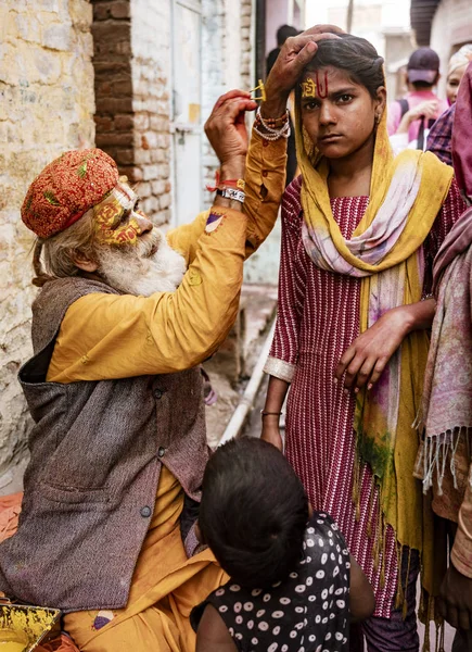 Starší muž maluje symboly pomocí zlaté malby na čelo ženy — Stock fotografie