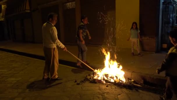 Cuenca, Ecuador - December 31, 2018 - Family stokes street bonfire at midnight on New Years Eve burning Old Year effigy — Stock Video