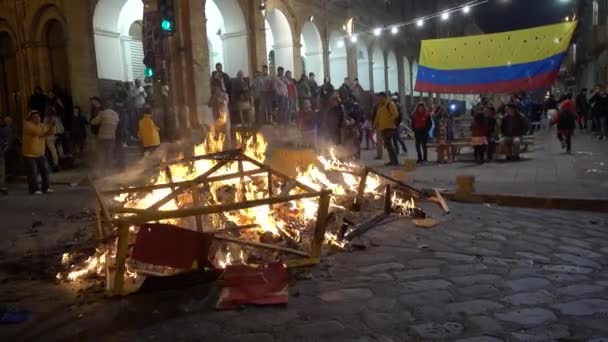 Cuenca, Ecuador - 31 de diciembre de 2018 - La gente ve hogueras callejeras a medianoche en Nochevieja con bandera ecuatoriana en el fondo — Vídeos de Stock