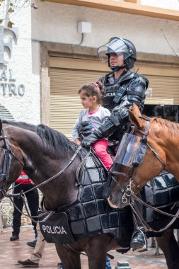 Cuenca, Ekvador - 13 Ağustos 2015 - Küçük bir kız polisin kucağında ata biner