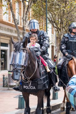 Cuenca, Ekvador - 13 Ağustos 2015 - Küçük bir kız polisin kucağında ata biner