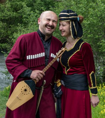Mestia, Georgia - 11 Haziran 2016 - Geleneksel ortaçağ kıyafetleri içindeki kadın ve erkek bir müzik aleti tutarken güldüler