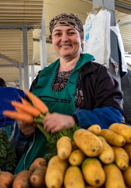 Taşkent, Özbekistan - 18 Mayıs 2017: Kadın satıcı havuç ve patateslerini göstermekten gurur duyar