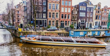 Amsterdam, Hollanda - 24 Mart 2016 Amsterdam 'da bir kanalda turist botu yüzüyor