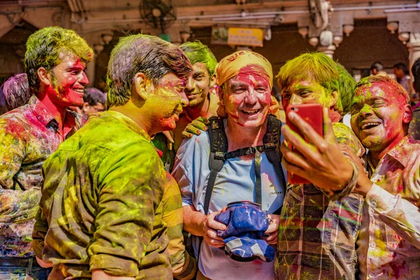 Barsana, India - February 23, 2018 - A tourist with camera in underwater case surrounded by Indians wanting a selfie with him during Holi festival — Stock Photo, Image