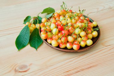 Sarı-kırmızı tatlı kiraz bir plaka üzerinde bir ahşap tabl