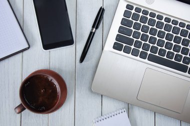 Bir fincan kahve ile bir dizüstü bilgisayar, bir dizüstü bilgisayar, bir smartphone ve bir kalem beyaz masaüstünde. İş concep
