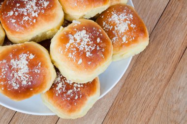 Ahşap bir masada bir tabak üzerinde taze pişmiş çörekler