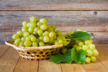 Sarı ve yeşil çekirdeksiz üzümler ahşap bir masada hasır bir tabakta