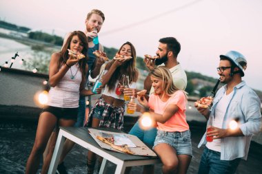 Bir grup mutlu genç arkadaş çatıda parti veriyor.