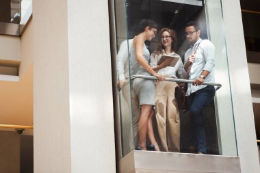 Asansörde konuşan genç çekici iş adamları resmini