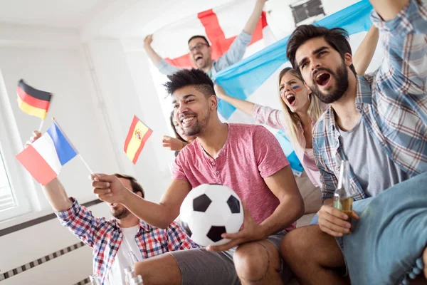 Young group of friends watching sport on television and cheering