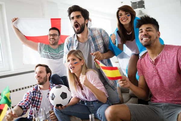Young group of friends watching sport on television and cheering