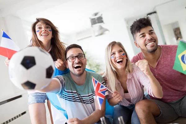 Young group of friends watching sport on television and cheering