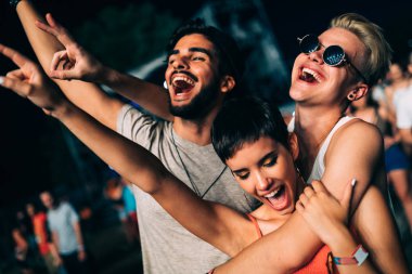 Mutlu genç arkadaşlar müzik festivalinde eğleniyor.