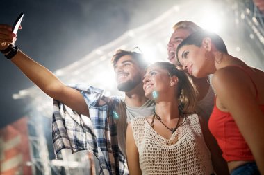 Mutlu genç arkadaşlar müzik festivalinde eğleniyor.