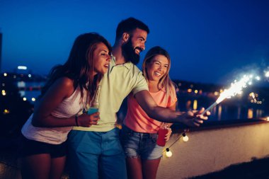 Bir grup mutlu arkadaş çatıda kutlama yapıyor.