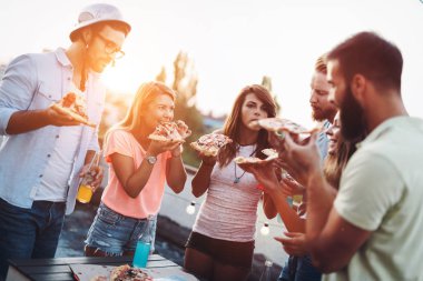 Bir grup mutlu genç arkadaş çatıda parti veriyor.