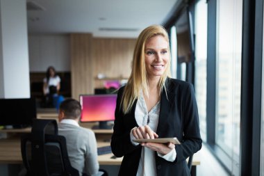 Modern ofiste dijital tablet kullanan çekici bir iş kadını