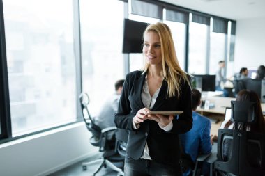 Modern ofiste dijital tablet kullanan çekici bir iş kadını