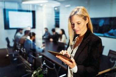 Modern ofiste dijital tablet kullanan çekici bir iş kadını