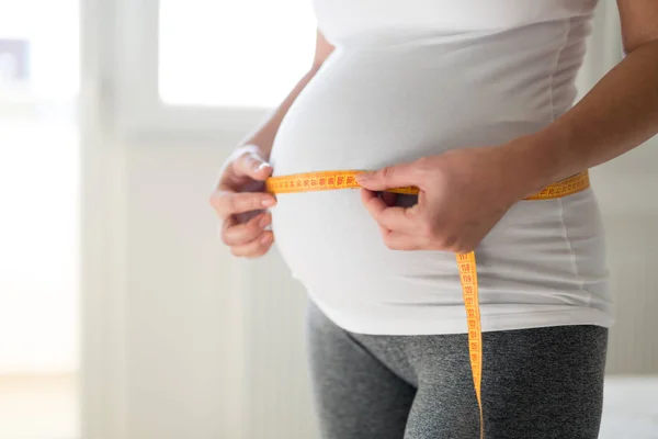 妊娠中の女性が彼女の胃を巻尺で測定 — ストック写真