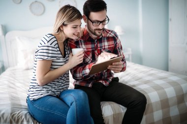 Genç mutlu çift yatak odasında dijital tablet kullanma