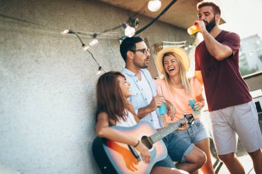 Bir grup mutlu genç arkadaş çatıda parti veriyor.