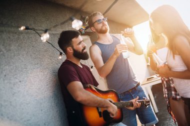 Bir grup mutlu genç arkadaş çatıda parti veriyor.