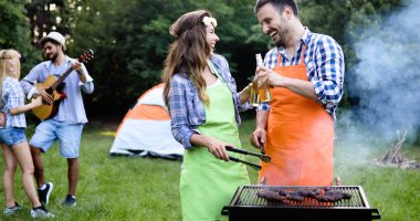 Neşeli arkadaşlar doğada vakit geçirip barbekü yapıyorlar.