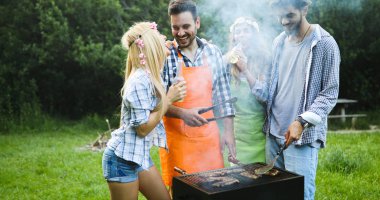 Neşeli arkadaşlar doğada vakit geçirip barbekü yapıyorlar.