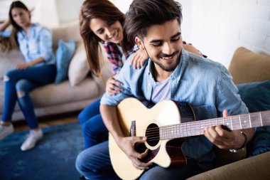 Genç yakışıklı adam güzel kız arkadaşı için gitar çalıyor.