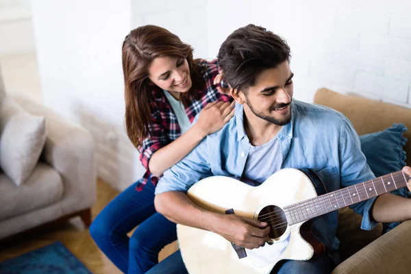 Jovem homem bonito tocando guitarra para sua namorada — Fotografia de Stock