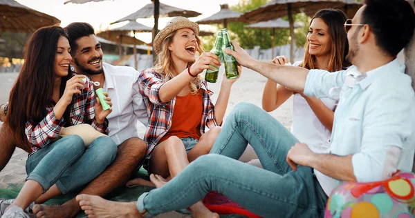 Group of young friends laughing and drinking beer at beach