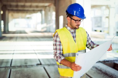 Genç iş adamı inşaat sitesi mühendis mavi baskı ile