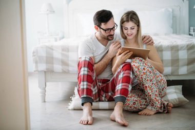 Genç mutlu çift yatak odasında dijital tablet kullanma