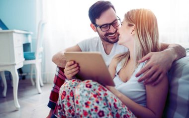 Genç mutlu çift yatak odasında dijital tablet kullanma