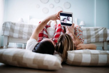 Genç mutlu çift yatak odasında dijital tablet kullanma